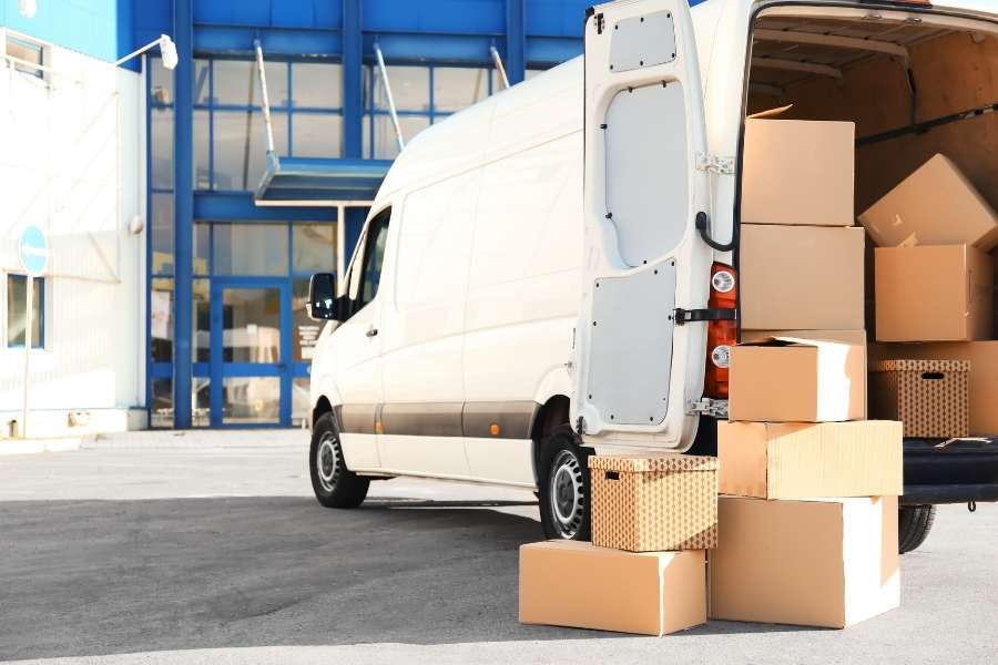 Un camion blanc ouvert et rempli de cartons pour un déménagement réussi devant un bâtiment.