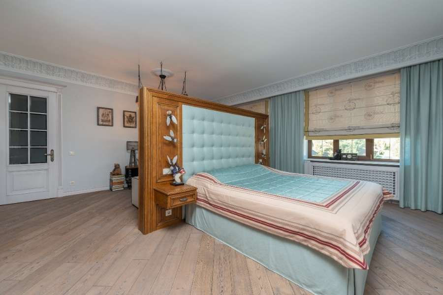 Une grande chambre à coucher lumineuse avec une imposante tête de lit en bois massif et capitonnée