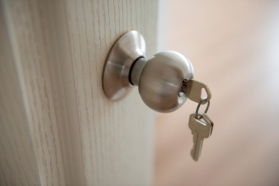 Gros plan sur une clé insérée dans le bouton métallique d'une poignée de porte, représentant le cas où une clé neuve accroche dans une serrure neuve.