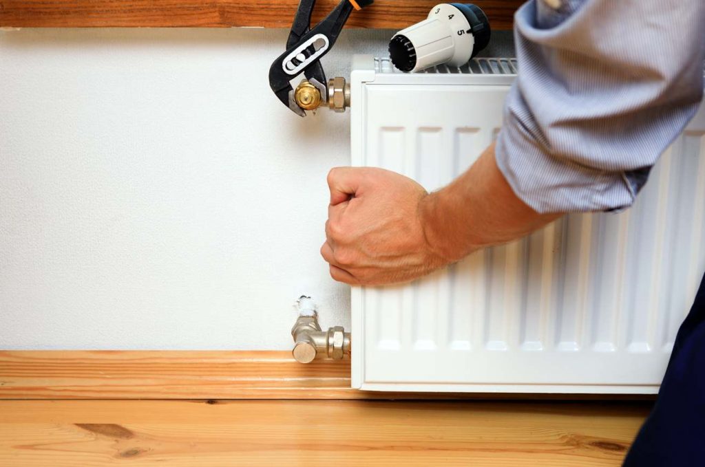 Un technicien vérifie le raccordement d'un radiateur afin d'éviter les erreurs pose chauffage central